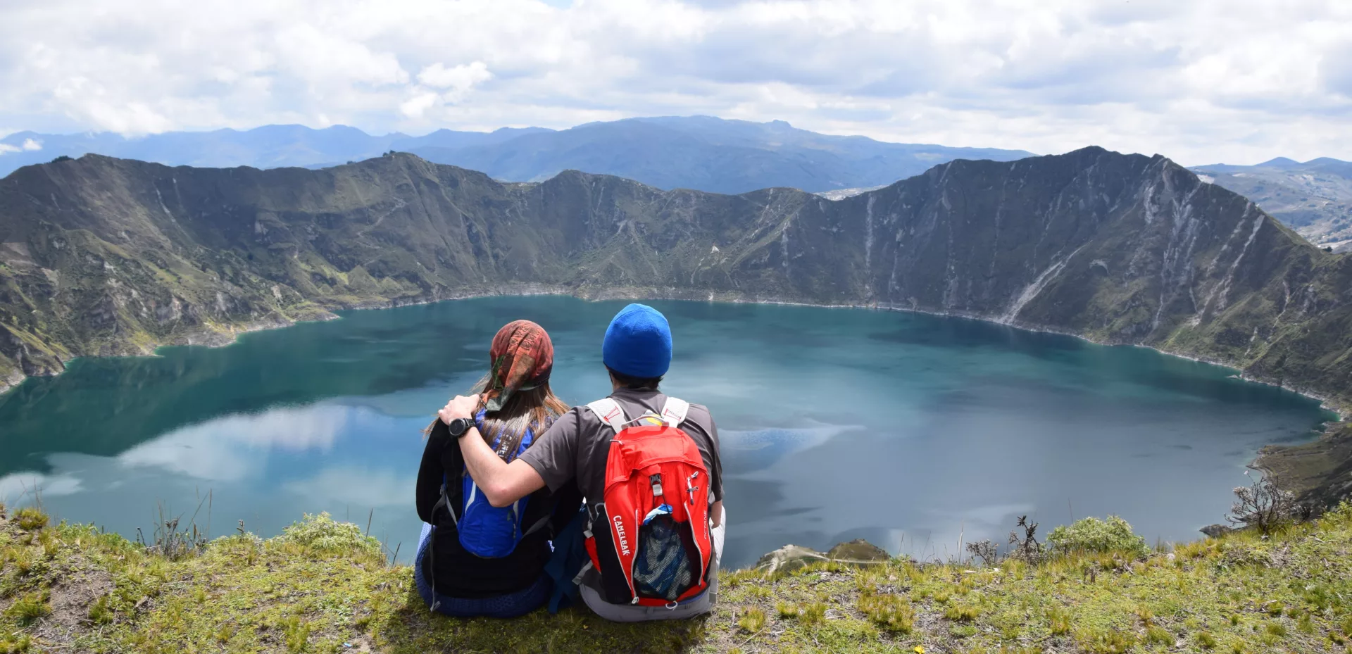 To personer sitter og ser over en innsjø i fjellene i Ecuador