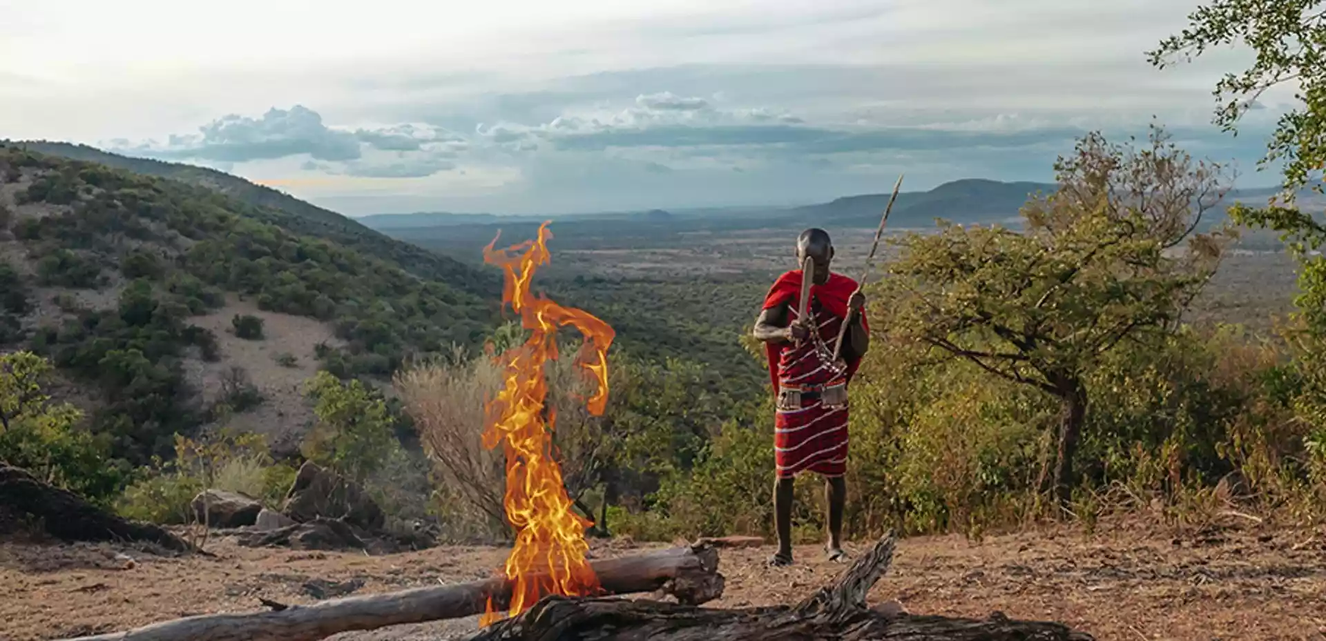 En man fra Masai stammen gjør klar en bål i på et lite fjell omgitt av afrikansk natur.