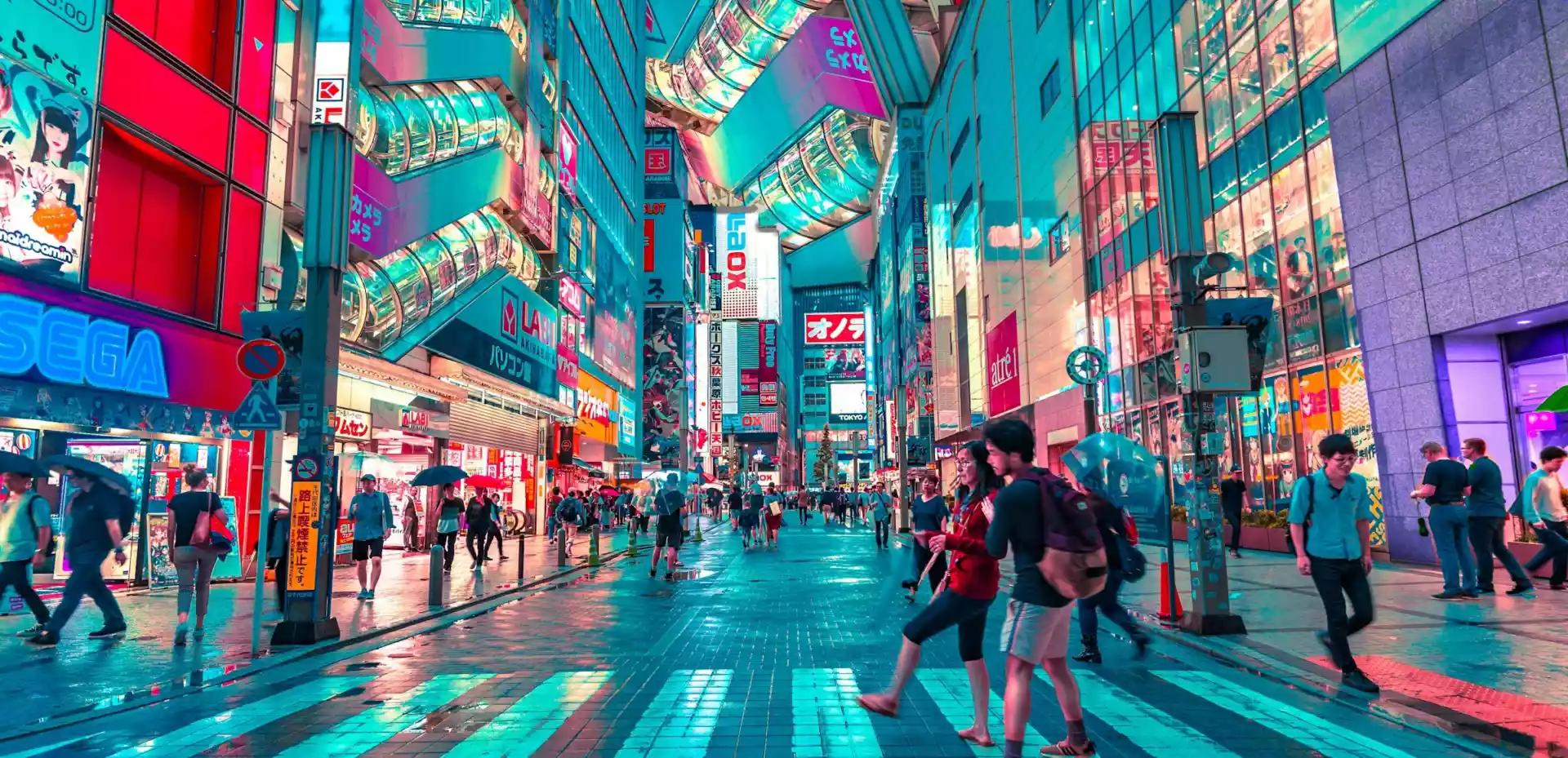 Gate i Tokyo omgitt av høye bygninger og neonlys. Gaten er fylt av mennesker både på veien og på gangfelt.