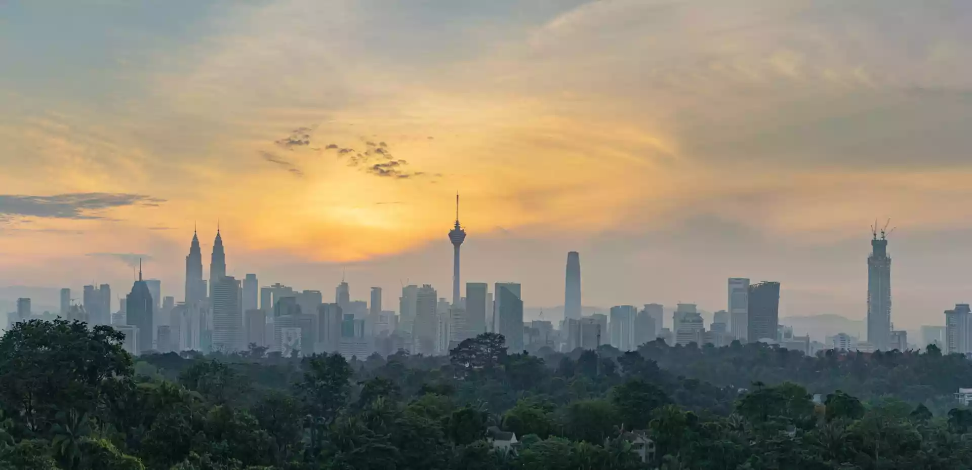 Overblikk over Kuala Lumpur i solnedgang med byens skyline og kjente bygninger opplyst i kveldslyset.