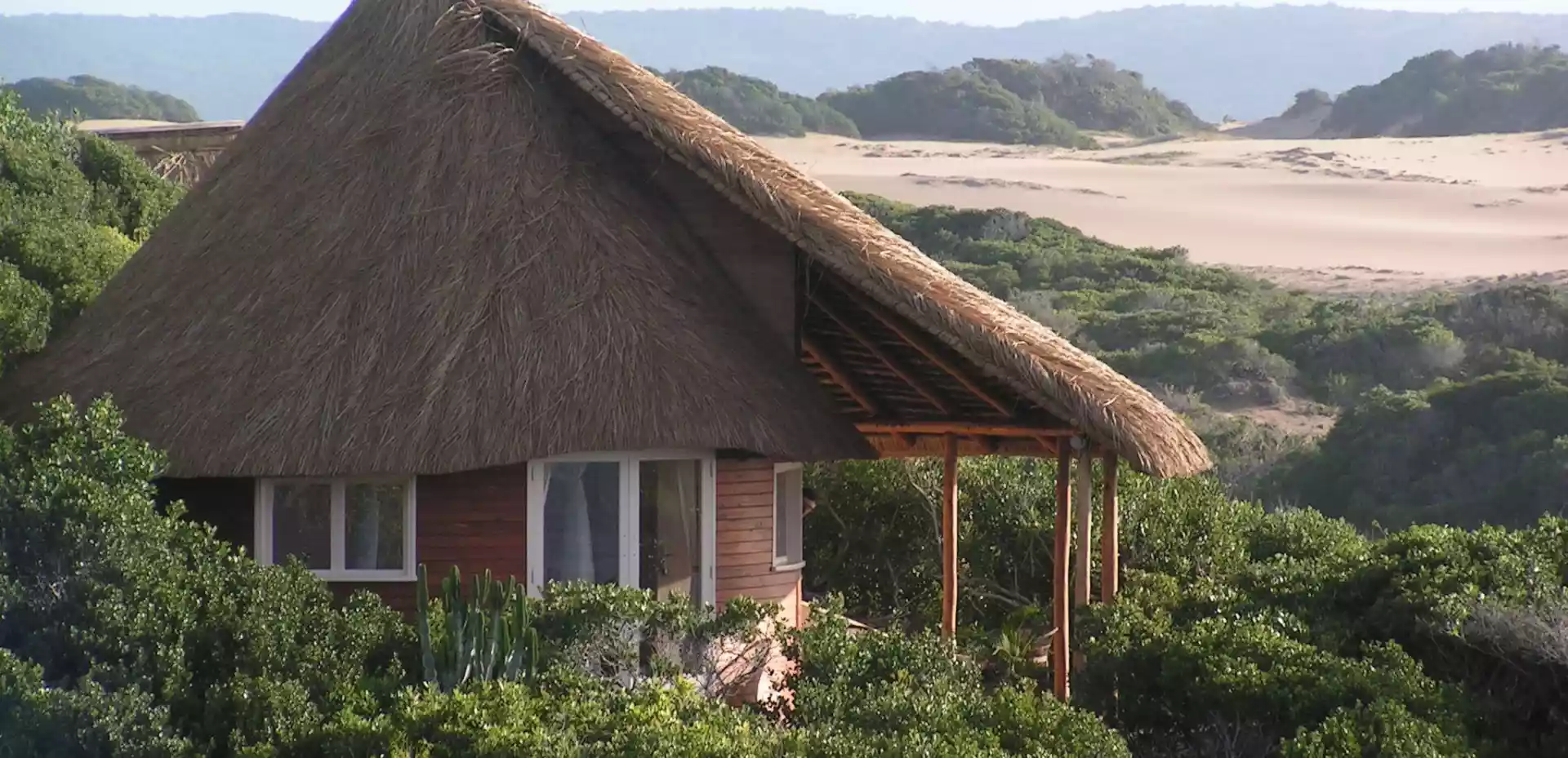 På den pittoreske Dune de Dovela ser vi en sjarmerende liten bungalow, omgitt av frodig vegetasjon og en bølgende strandlinje som møter det endeløse havet i horisonten.