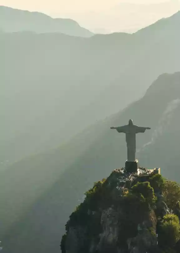 Kristus Frelseren i Rio de Janeiro, står på et fjell over Rio de Janeiro. Solstråler fra en lav sol skinner over de omkringliggende fjellene.