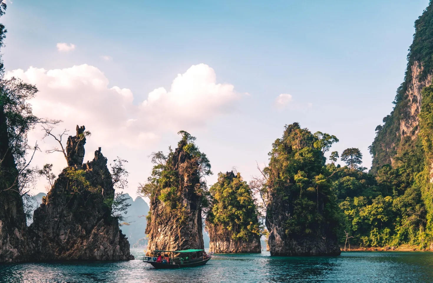 Klipper i Khao Sok med blå himmel og hav, og trær på klippene.