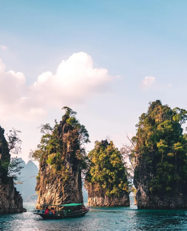 Klipper i Khao Sok med blå himmel og hav, og trær på klippene.