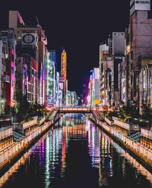 En elv i Osaka, med høye bygg som lyser opp natten.
