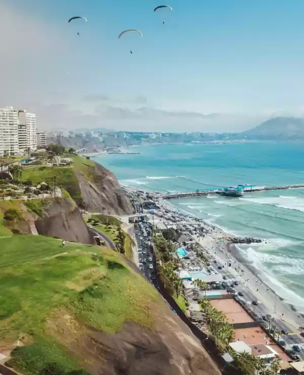 Overblikk over en klippe i Lima. Til venstre ligger høye hvite bygninger, og til høyre møter strand et blått hav.