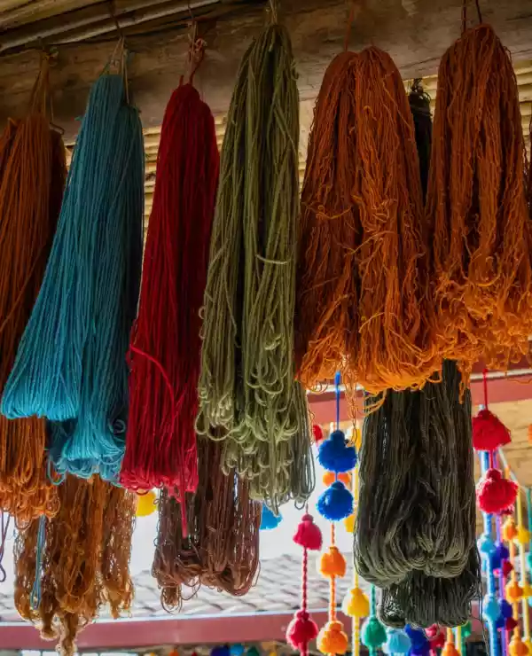 Tekstil i form av tråd i mange farger henger fra en butikk i Chinchero.