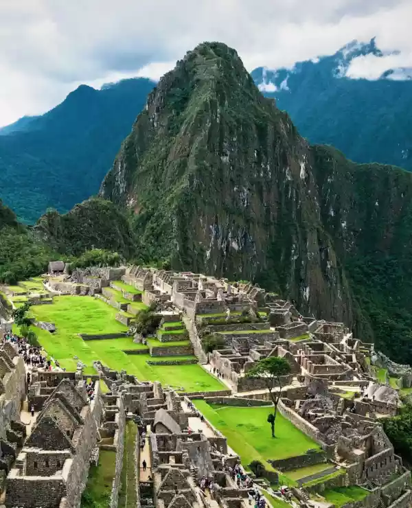 Overblikk over ruinene av Machu Picchu, med høye fjell og dype grønne daler.