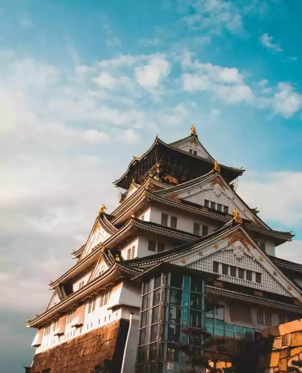 Et japansk slott med tradisjonell arkitektur, står i all sin prakt mot en klar, blå himmel.