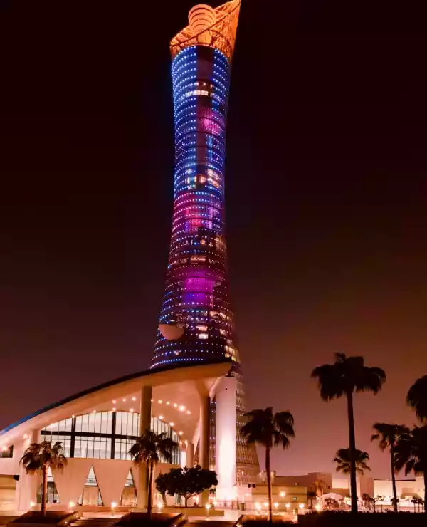 Et tårn i Doha strekker seg mot nattehimmelen, opplyst av blå og røde neonlys som lyser opp den mørke kvelden.