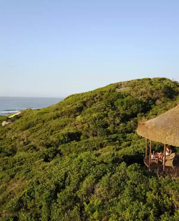 På den pittoreske Dune de Dovela ser vi en sjarmerende liten bungalow, omgitt av frodig vegetasjon og en bølgende strandlinje som møter det endeløse havet i horisonten.