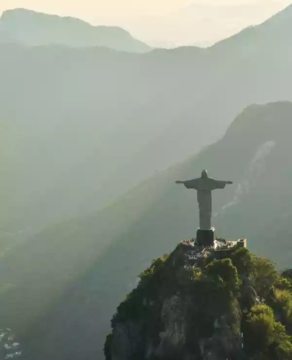 Kristus Frelseren i Rio de Janeiro, står på et fjell over Rio de Janeiro. Solstråler fra en lav sol skinner over de omkringliggende fjellene.