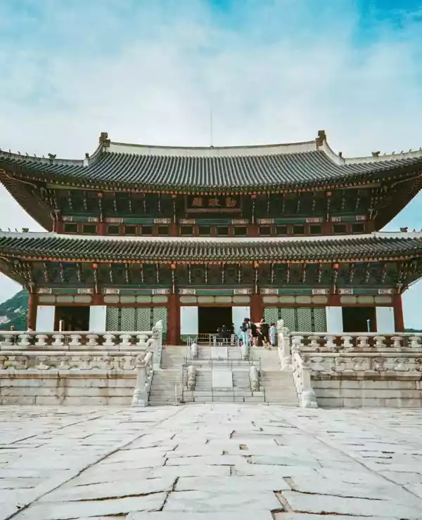 Tradisjonell Koreansk arkitektur i Seoul. Blå himmel og brolagt åpen plass foran tempelet.